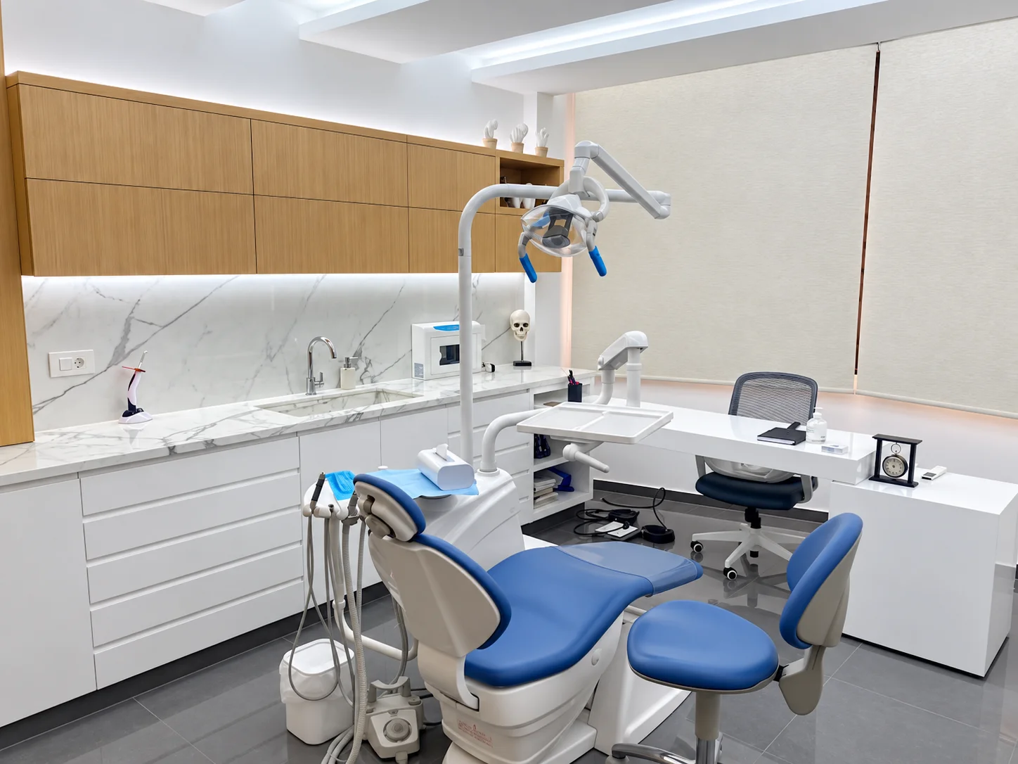 The blue treatment chair, wood cabinets and marble worktop in the Hazmieh clinic, in an AI-enhanced clinic photograph.
